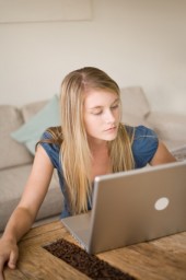 A blonde girl at home using a laptop computer